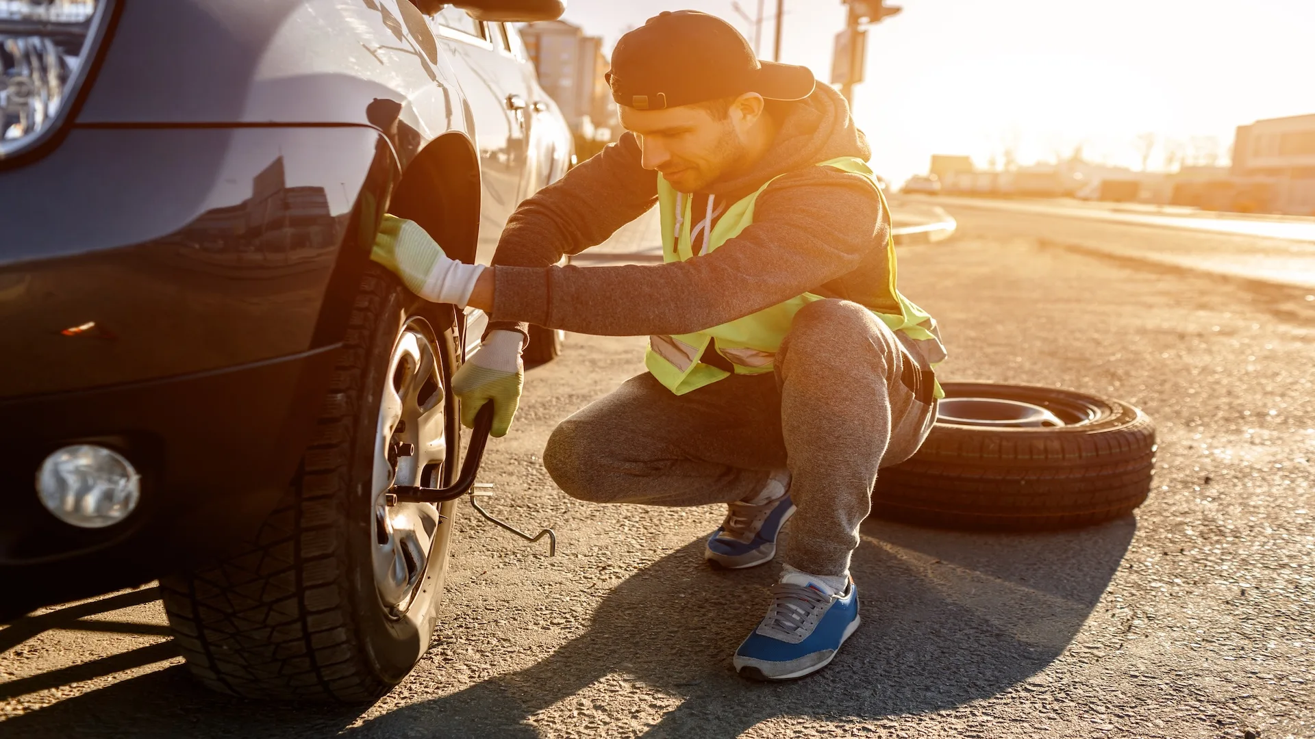 Roadside assistance technician preparing to change a flat tire for a stranded driver