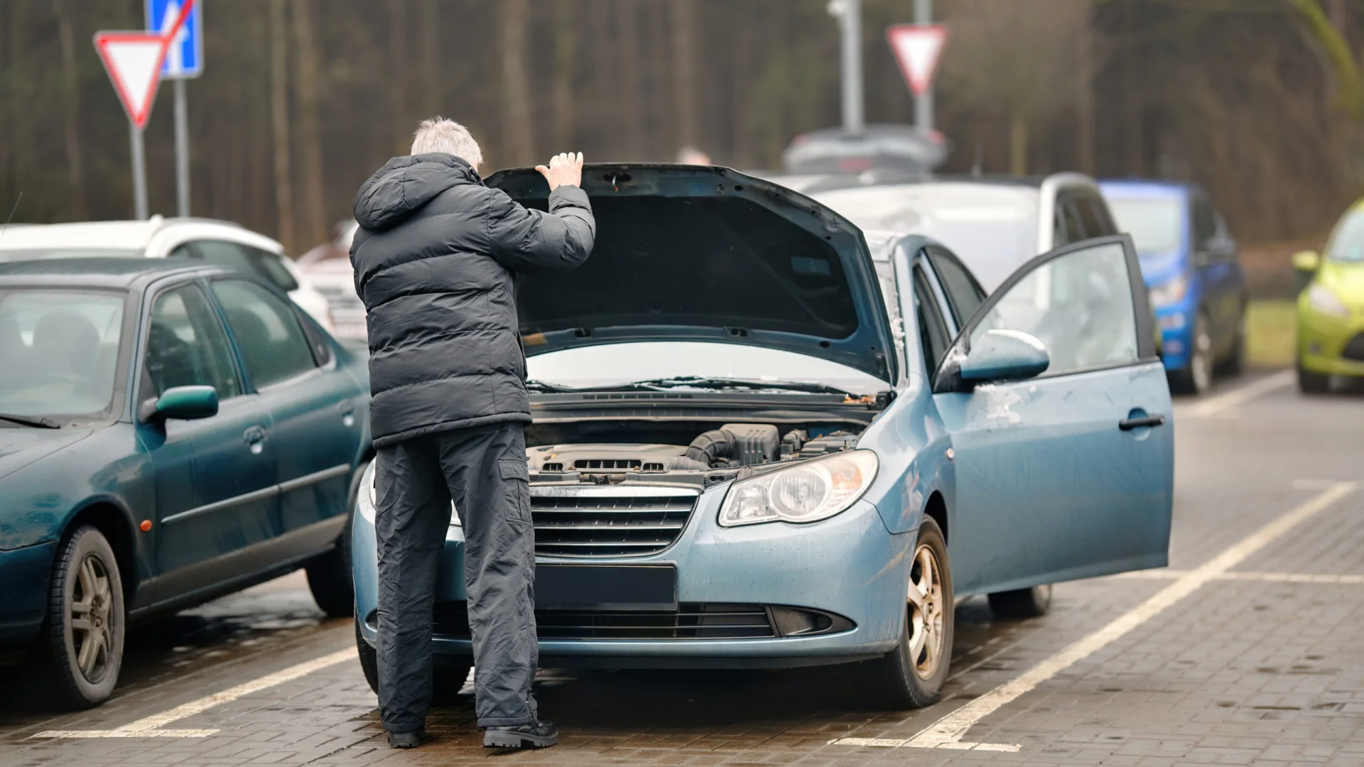 Driver checking under the hood after a roadside vehicle problem